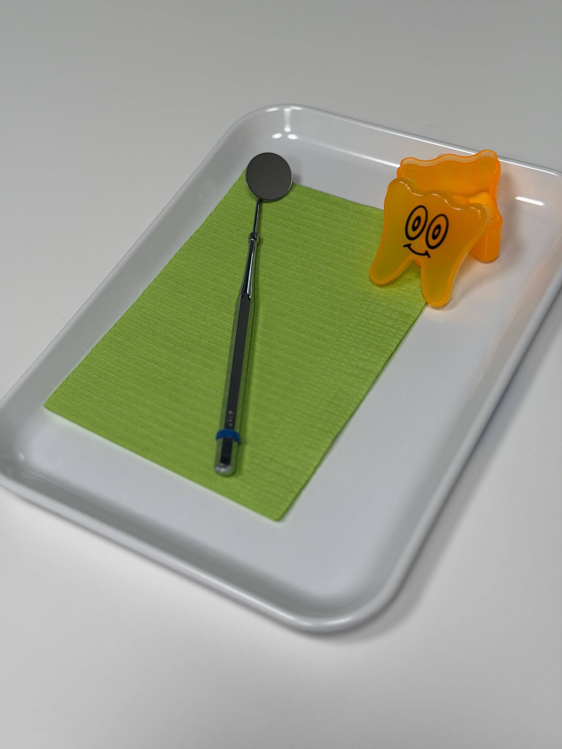 Kind beim Zahnarzt, Mund geöffnet, zur zahnärztlichen Untersuchung. Zahnarzt hält Instrumente, trägt Handschuhe.