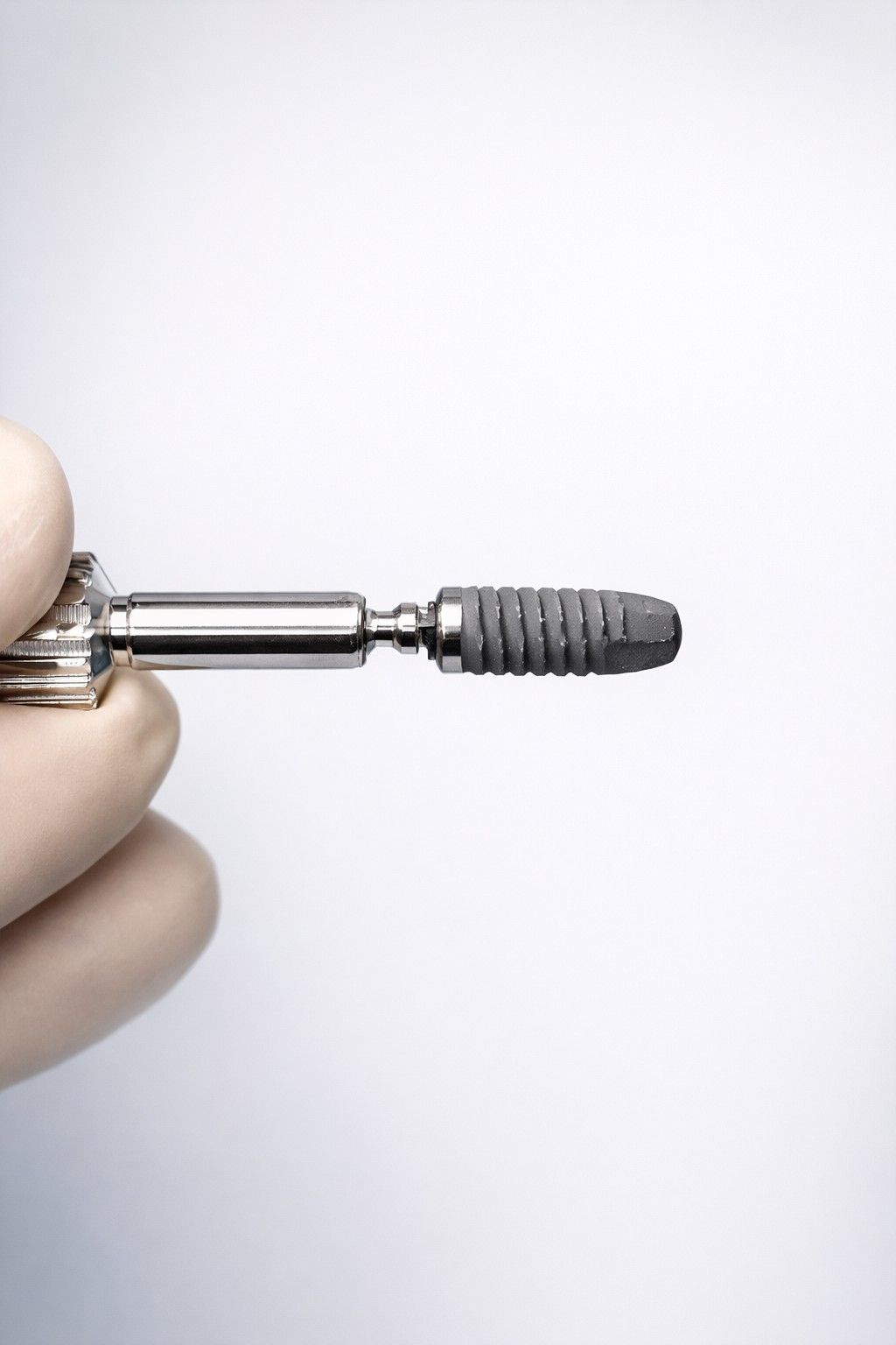 Zahnimplantatmodell mit schraubenartigem Befestigungselement im Kieferknochen, darüber eine weiße Zahnkrone, umgeben von weiteren Zähnen.