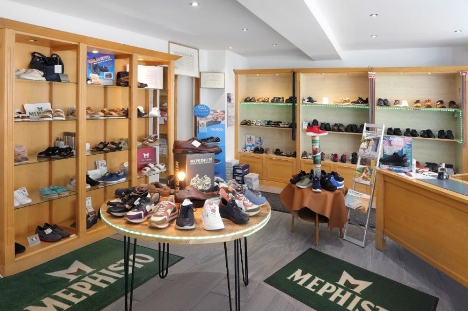 Innenansicht eines Mephisto-Schuhgeschäfts mit hölzernen Ausstellungsregalen und einem zentralen Tisch