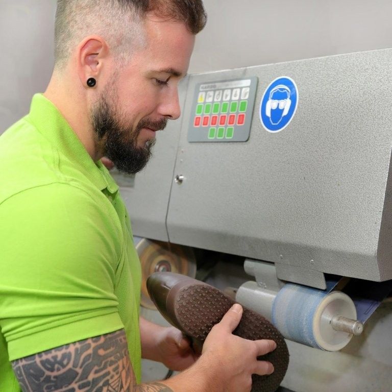 Eine Person, die ein hellgrünes Poloshirt trägt, benutzt eine professionelle Schleifmaschine