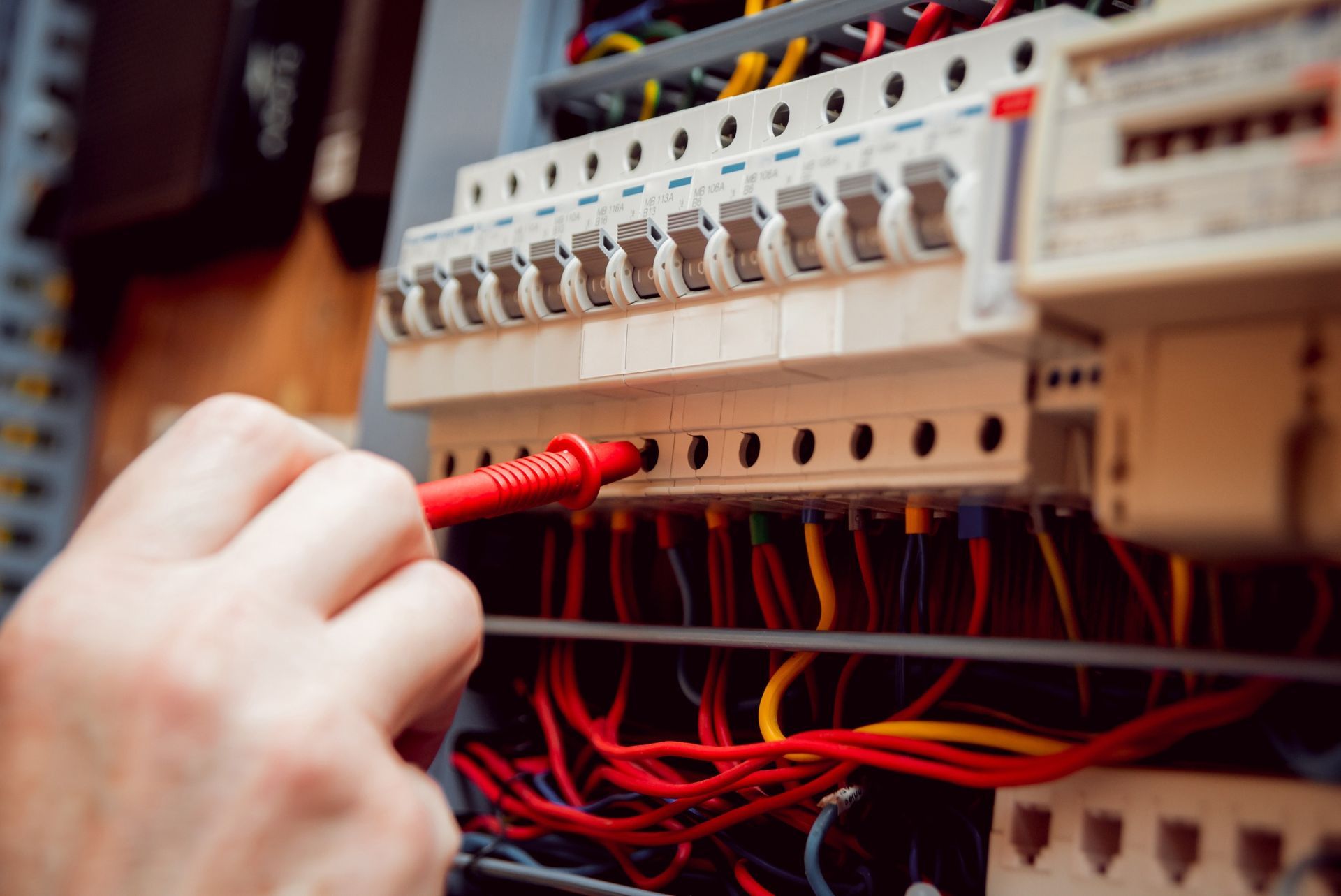 Una persona está trabajando en una caja eléctrica con un destornillador.