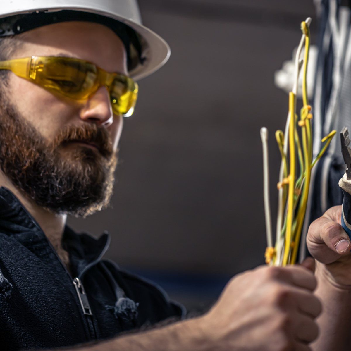 Un hombre que lleva casco y gafas de seguridad está trabajando con cables.