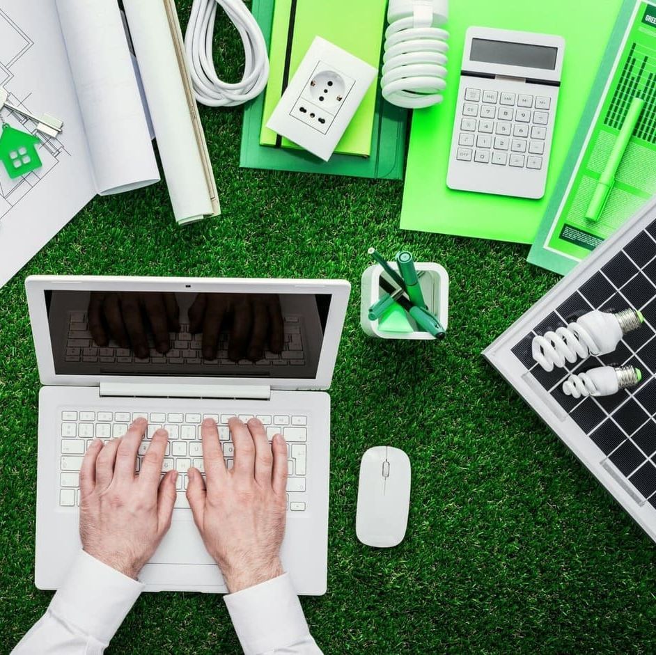 Una persona está escribiendo en una computadora portátil sobre el césped.
