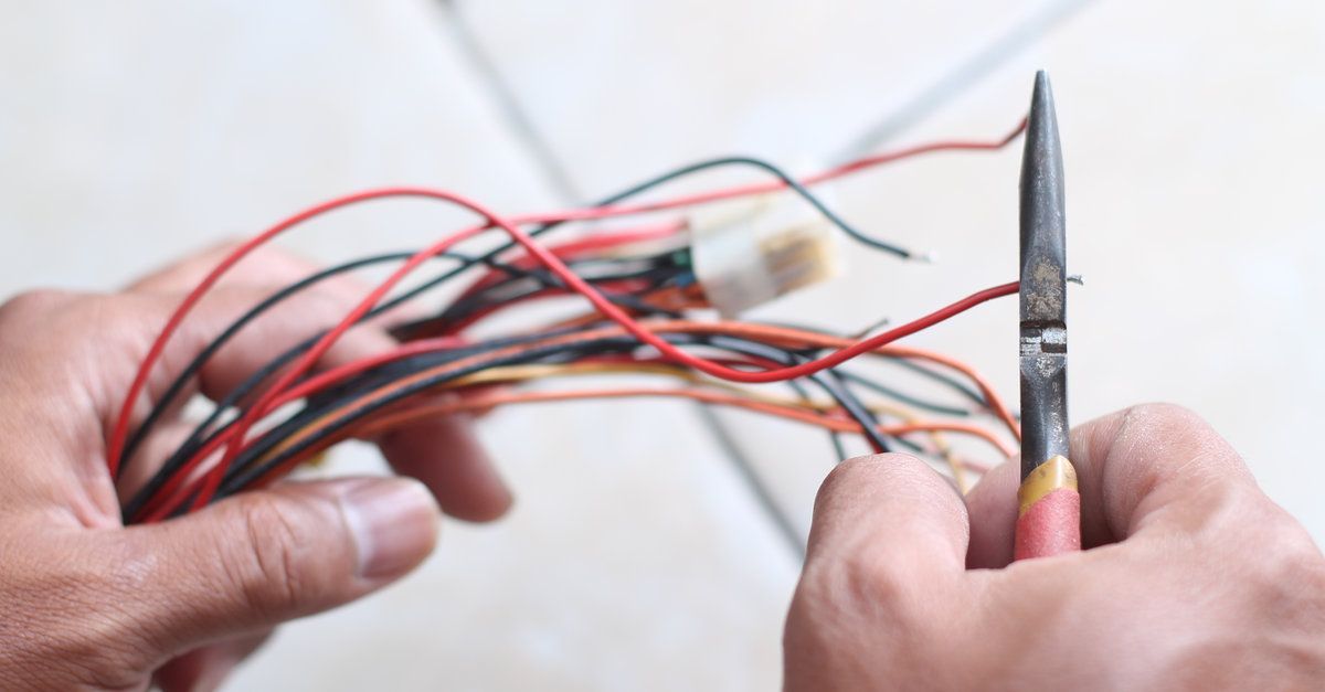 Una persona está cortando un montón de cables con una pinza.