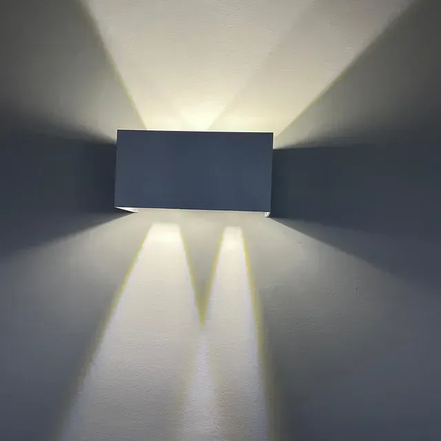 Una luz de pared brilla sobre una pared gris.