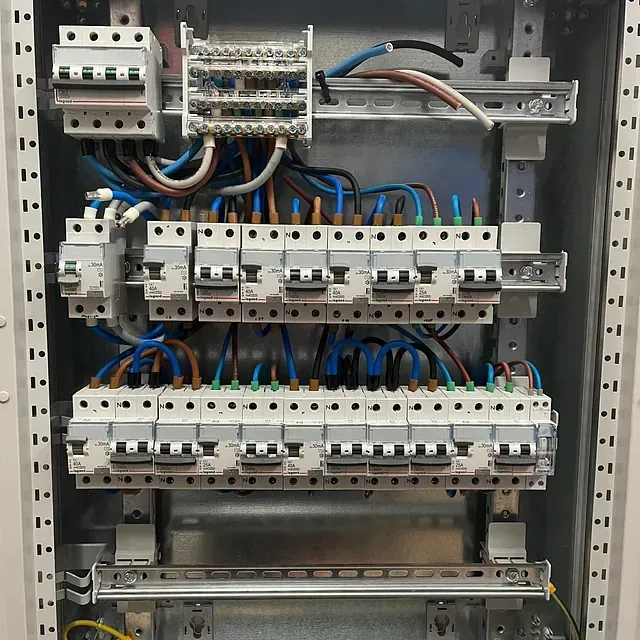 El interior de una caja eléctrica con muchos cables saliendo de ella.