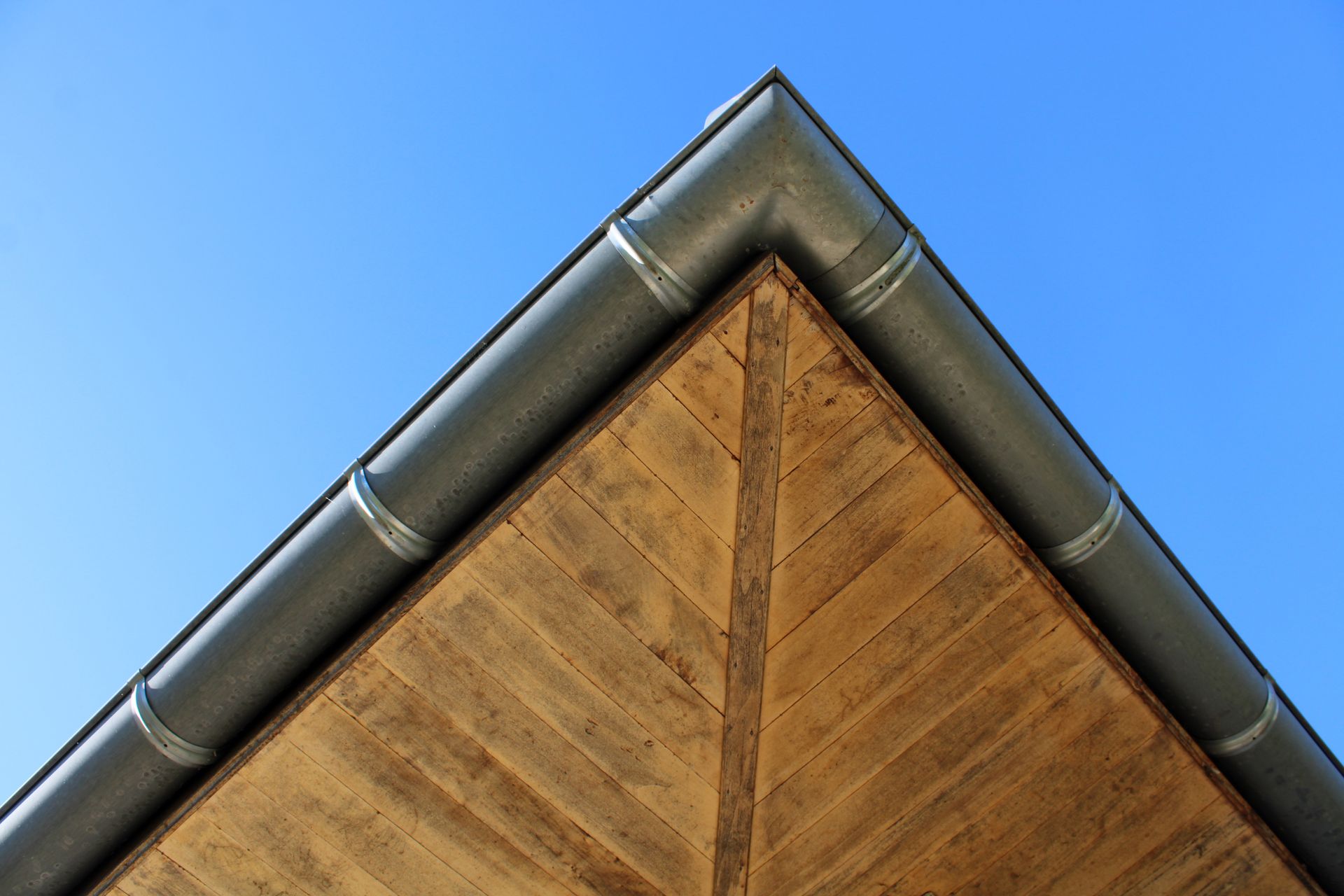 Gros plan sur le faîte d'un toit de maison avec des gouttières gris foncé sur fond de ciel bleu