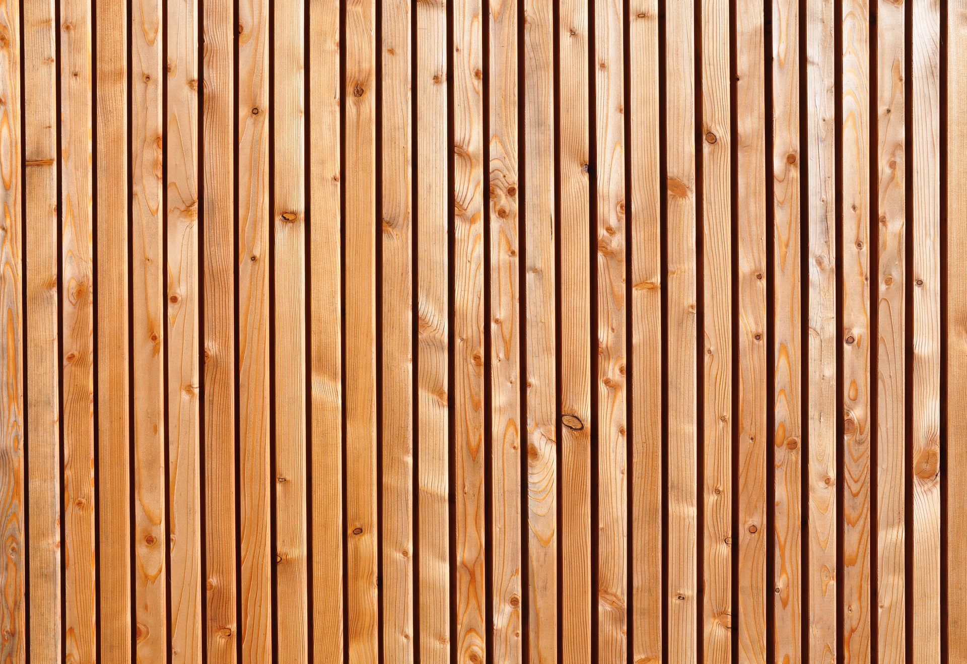 Mur en planches de bois verticales aux tons bruns chauds et aux nœuds apparents.