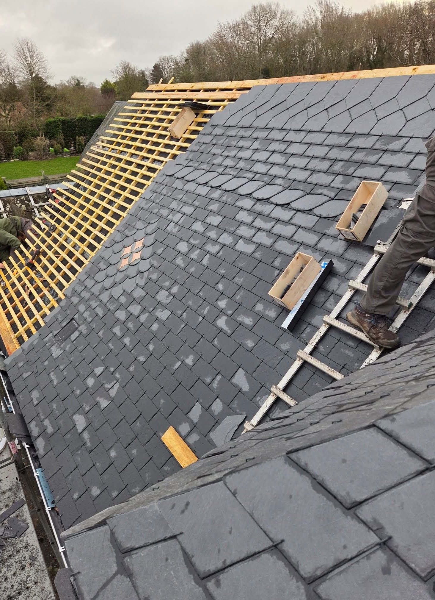 Toiture en construction avec bardeaux gris et liteaux de bois apparents sur une pente raide.