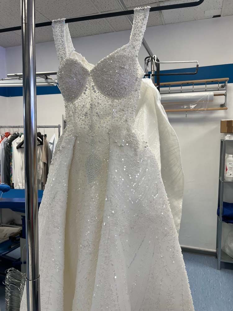 Ein weißes Brautkleid hängt in einem Zimmer an einer Kleiderstange.