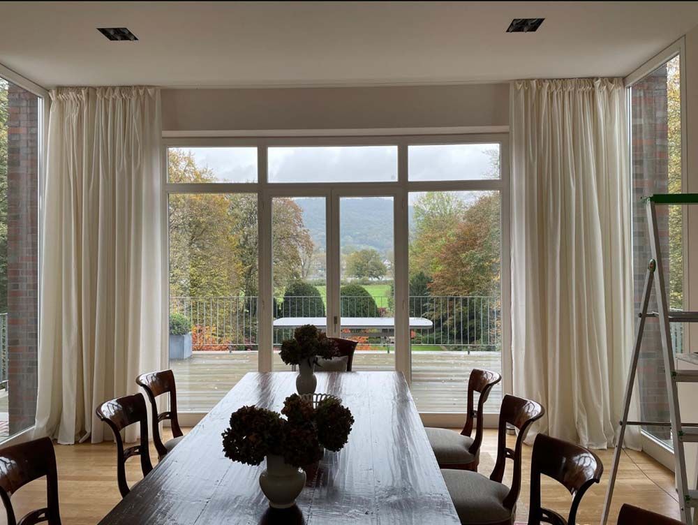 Ein Esszimmer mit einem großen Tisch und Stühlen und einer Leiter.