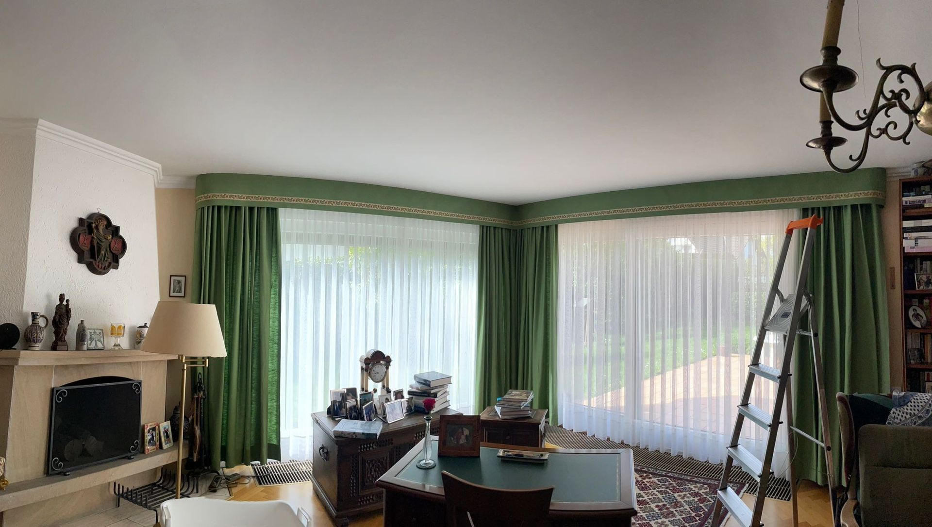 Ein Wohnzimmer mit grünen Vorhängen und einer Leiter in der Ecke.