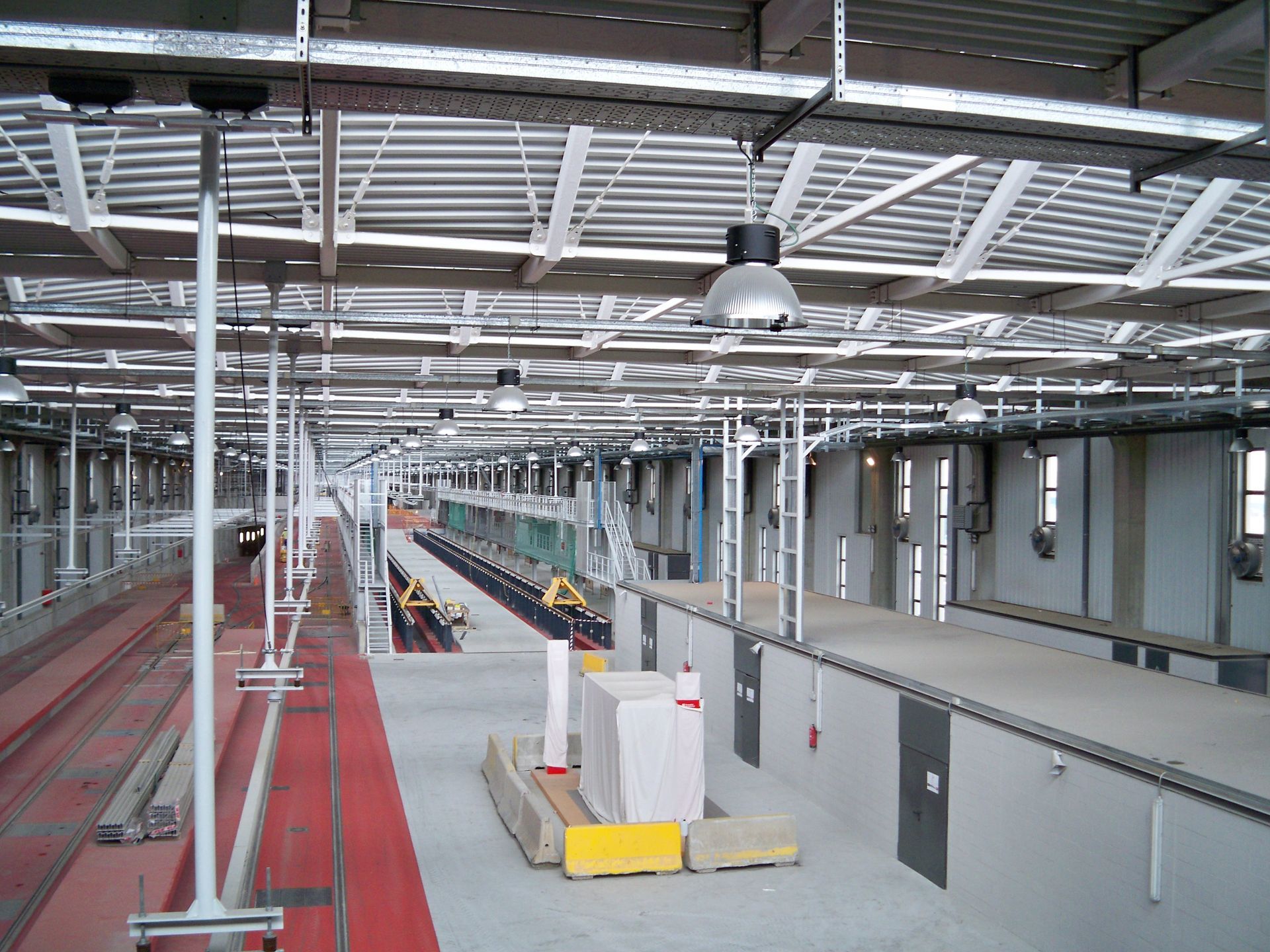 Dentro de una instalación de mantenimiento de trenes, con vías de tren, plataformas de trabajo e iluminación superior.