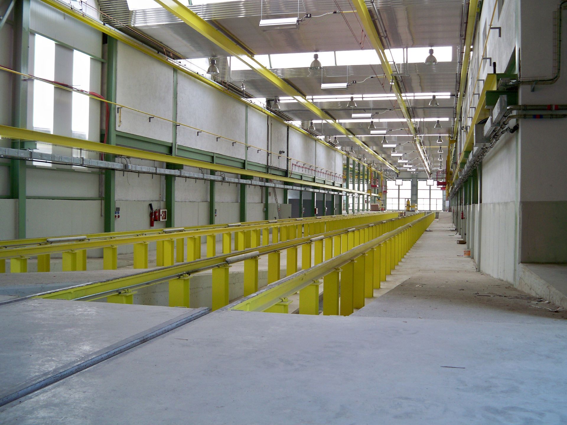 Taller industrial pintado de amarillo con barandillas elevadas y largas plataformas de trabajo.