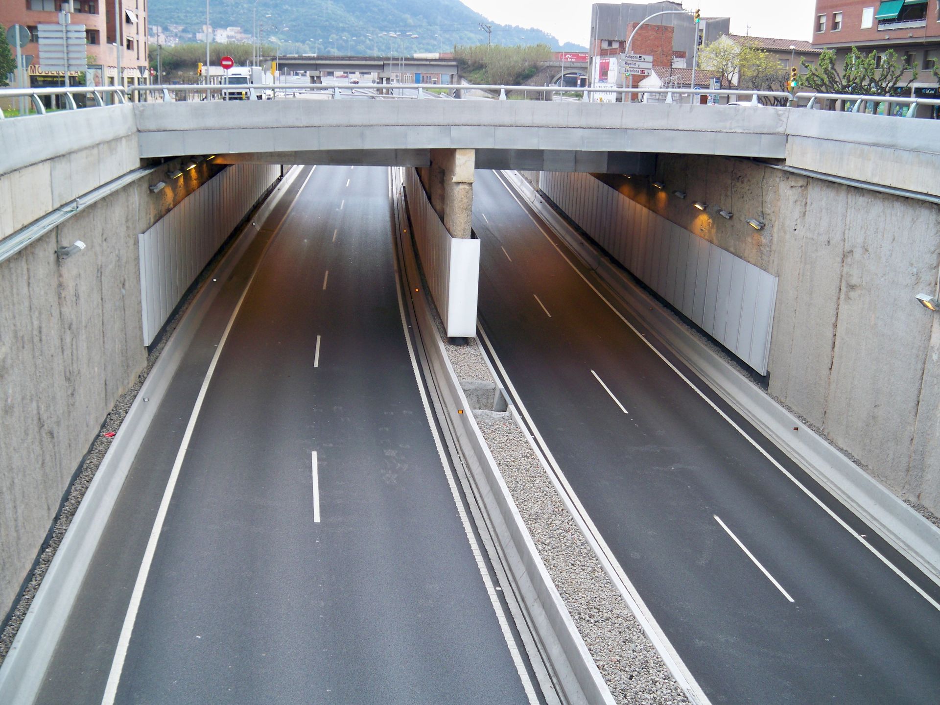 Vista elevada de un túnel de carretera de hormigón con dos carriles, debajo de un puente.