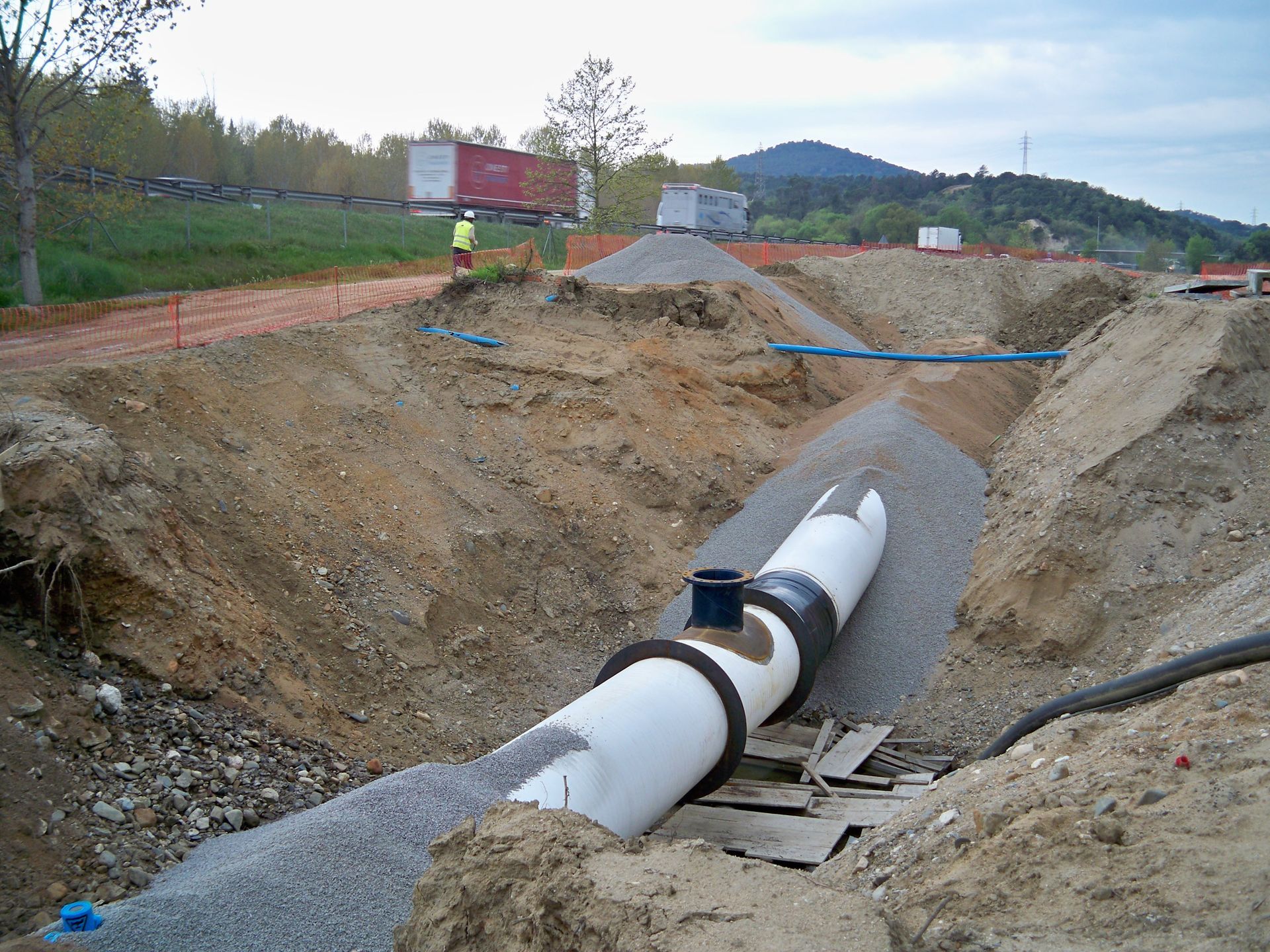 Obra con tubería enterrada. Grava, tierra y maquinaria pesada.