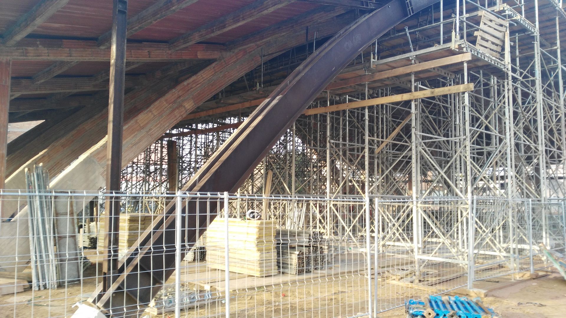 Interior de obra: andamios, vigas de acero, estructura de madera.