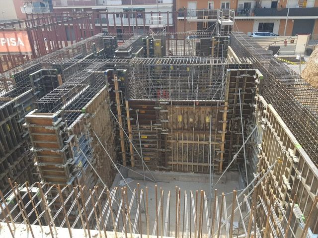 Obra de construcción con refuerzo de acero y encofrados de madera para cimentación de hormigón.
