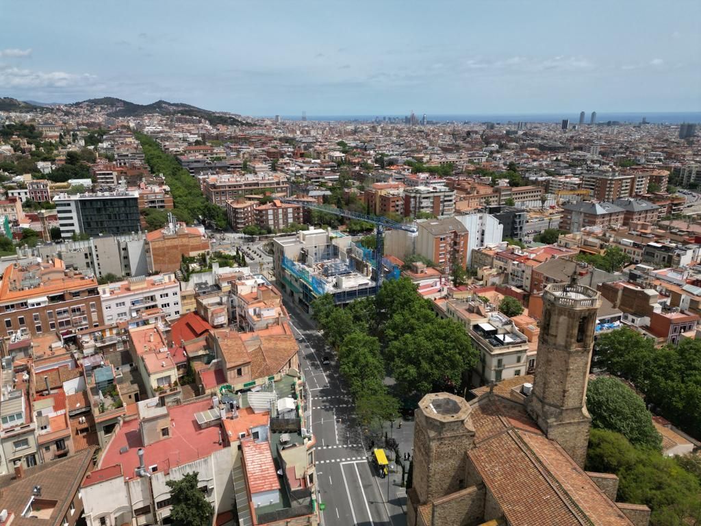 Vista aérea de Barcelona, ​​España, con edificios, calles y una iglesia con techo de tejas marrones bajo un cielo azul.