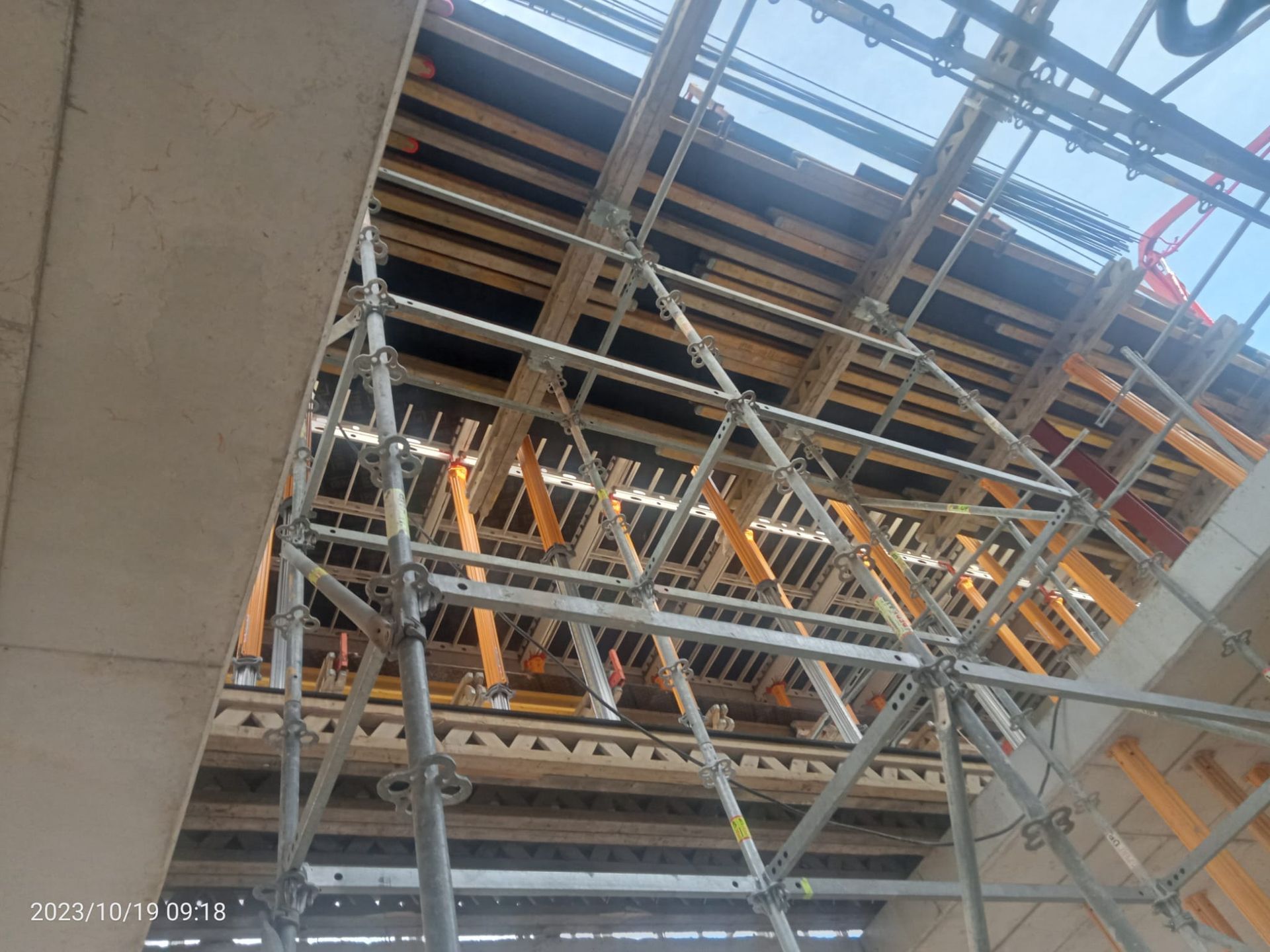 Andamio que sostiene un techo de encofrado de madera en una obra en construcción, visto desde abajo.
