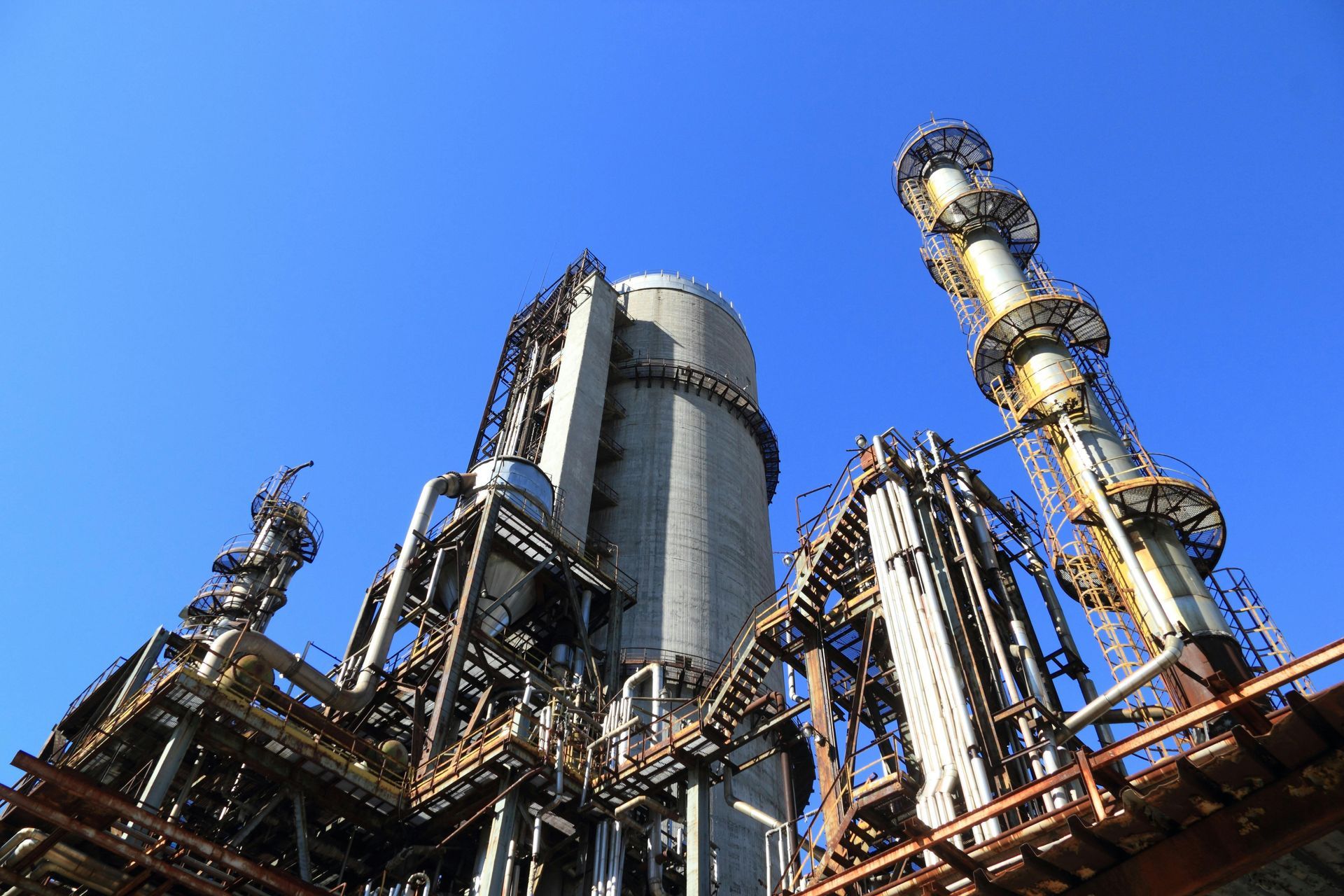 Complejo industrial con torres, tuberías, contra un cielo azul claro.