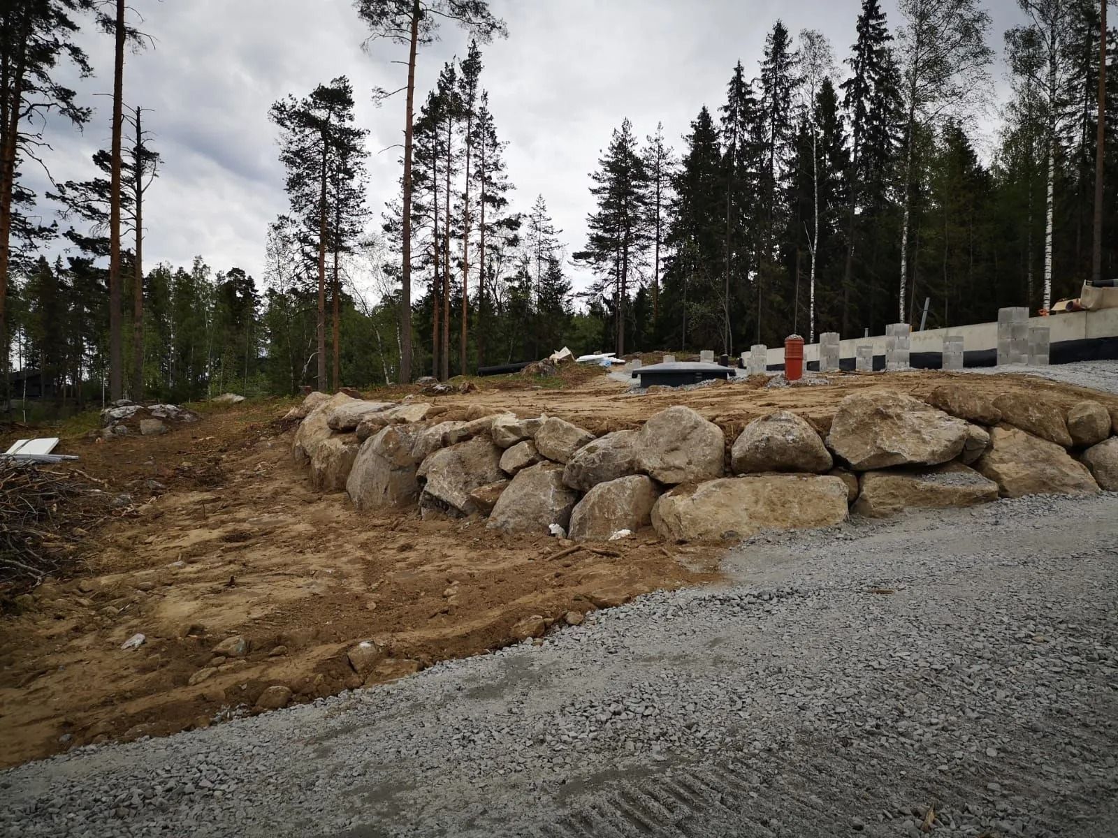 Kivinen tukimuuri soratien vieressä metsäisellä rakennustyömaalla