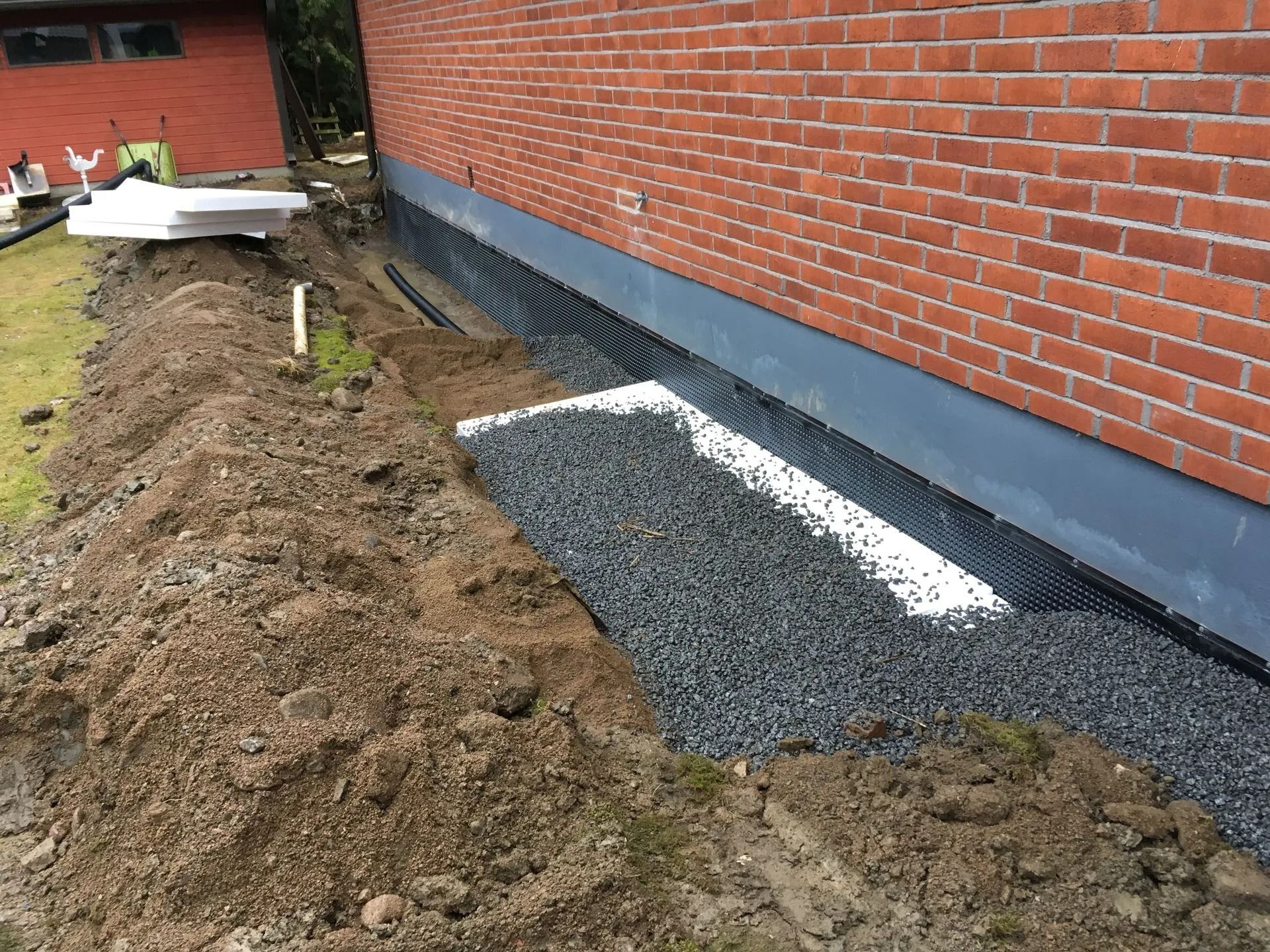 Sorakaivanto tiilitalon vieressä, lähellä tuoretta kaivettua maata