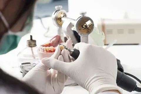 Un dentista está trabajando en una dentadura con una máquina.