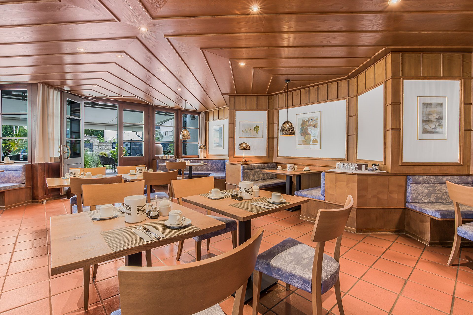 Essbereich mit gedeckten Tischen. Fenster bieten einen Blick nach draußen.