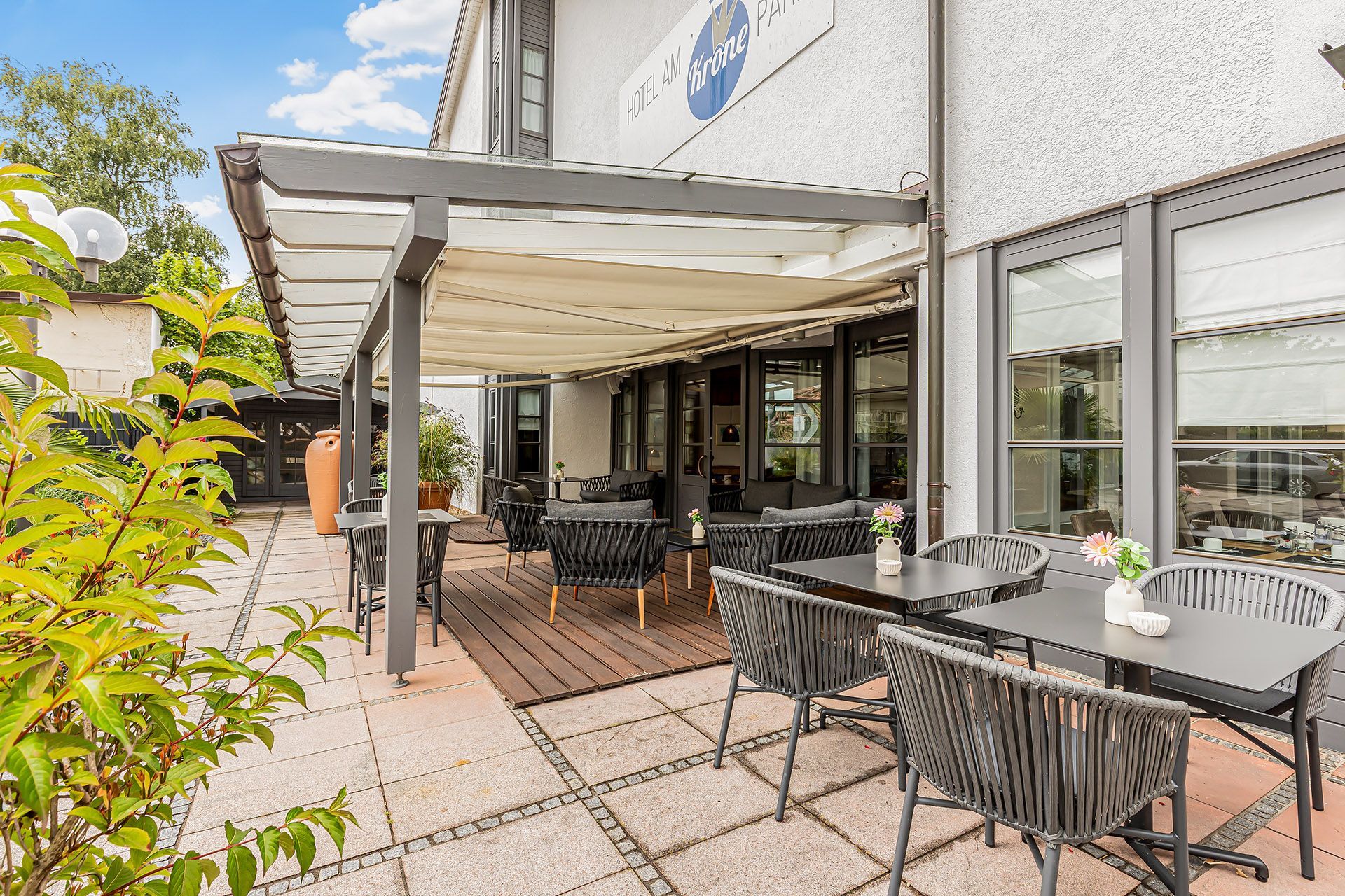 Terrasse im Freien mit Tischen, Stühlen und Überdachung.