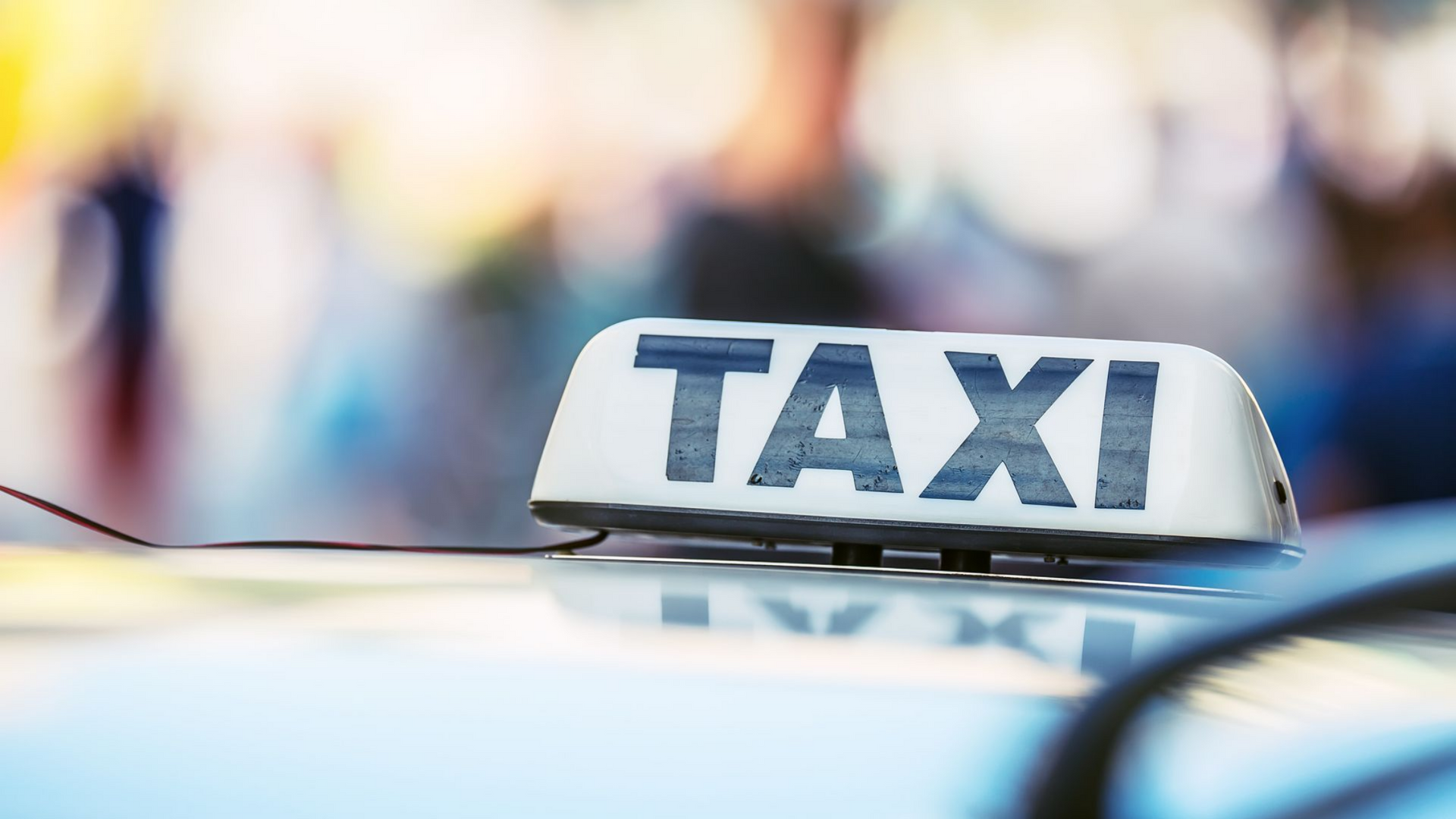 Panneau de taxi sur le toit d'une voiture, lumières de la ville floues en arrière-plan
