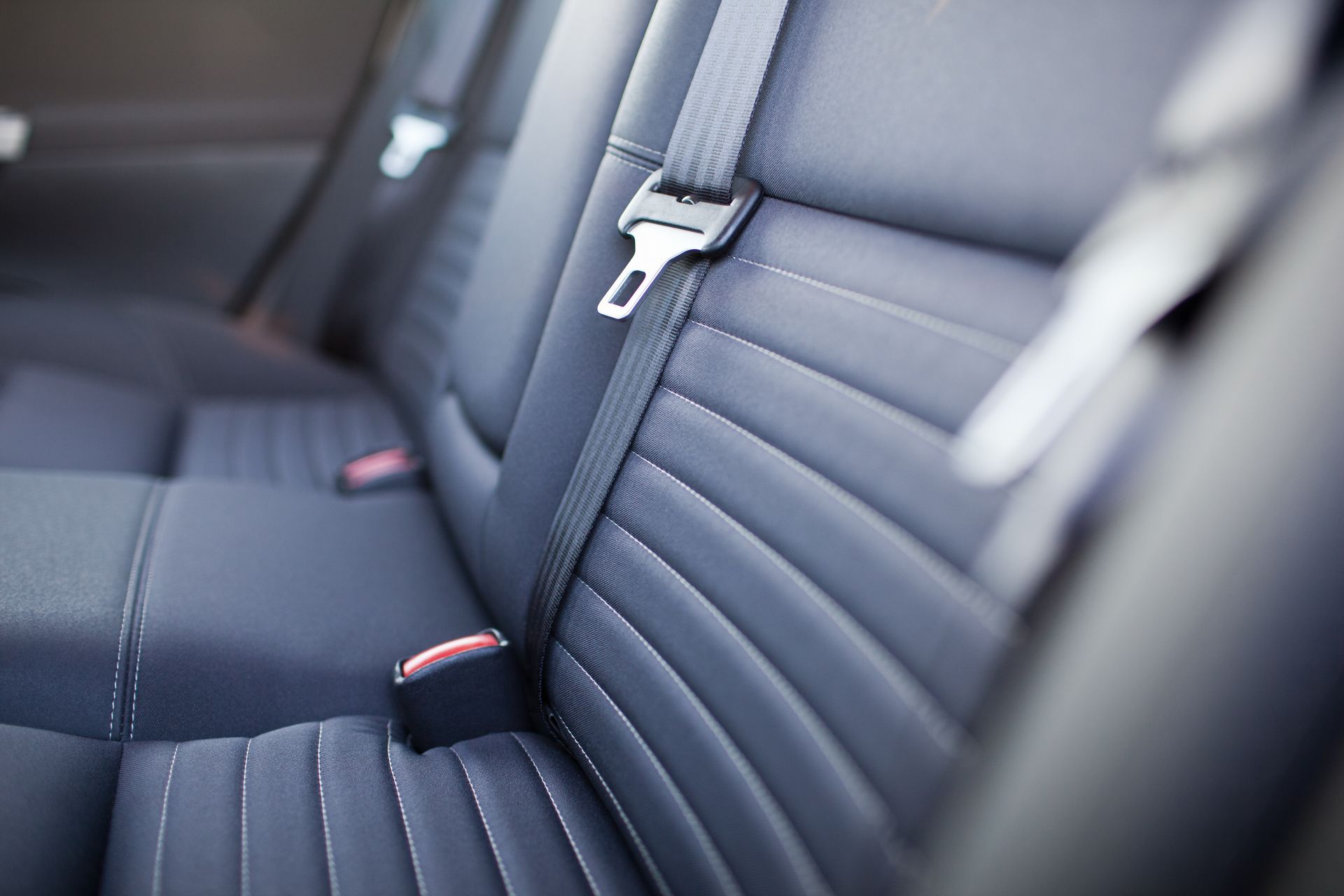 Intérieur de siège auto avec sellerie en cuir noir et ceinture de sécurité visible entre les sièges arrière