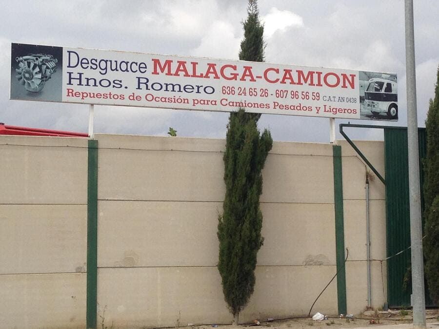 Un cartel de desguace Málaga-Camión cuelga sobre una valla.