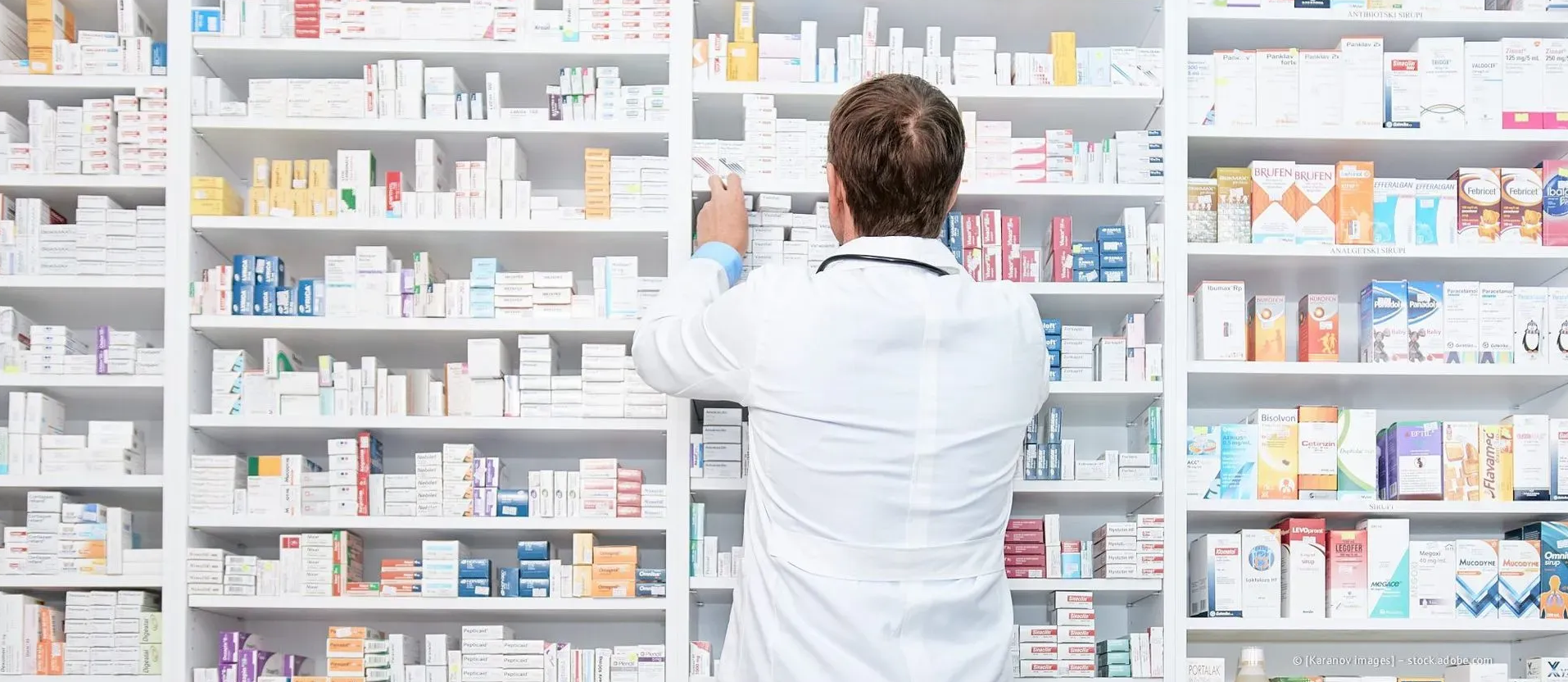 Ein Apotheker im weißen Kittel ordnet Medikamente in Regalen in einer Apotheke.