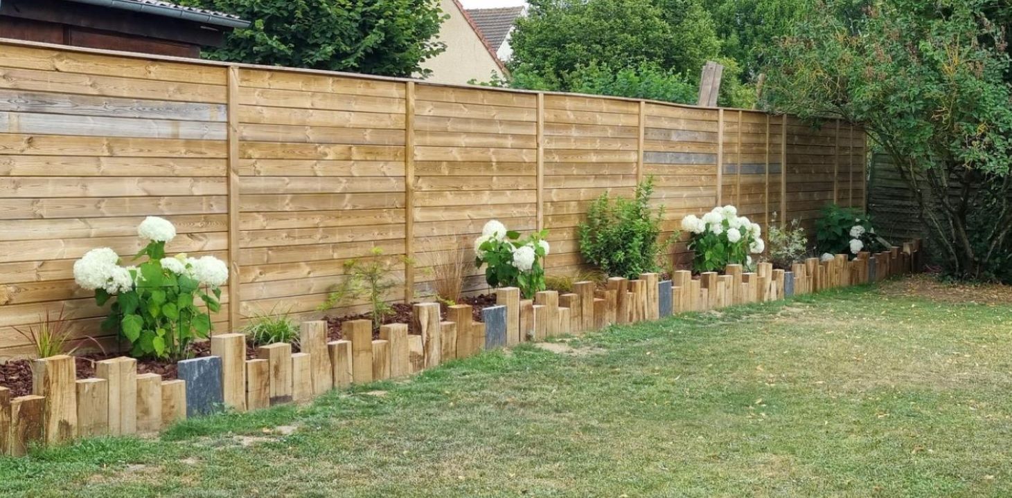 Clôture en bois avec des fleurs et une pelouse.