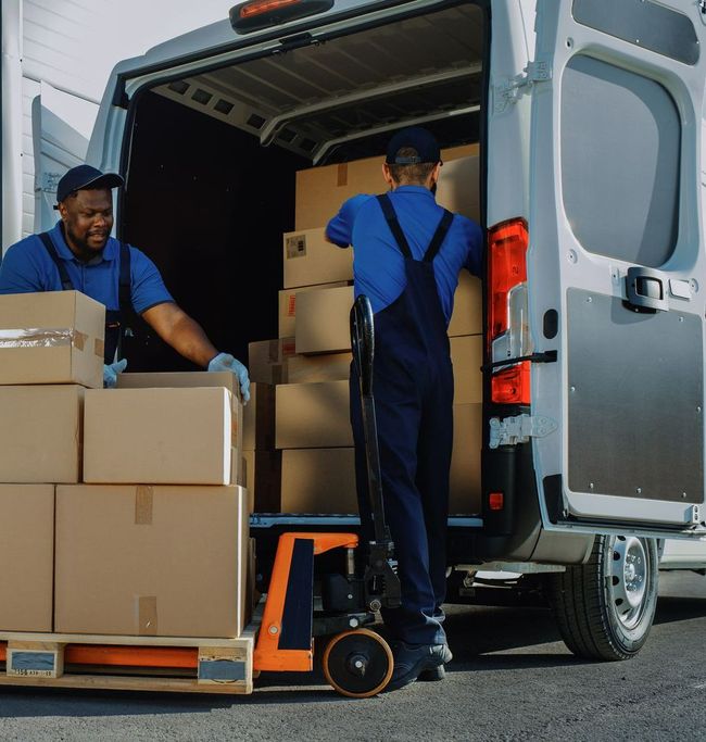 Des hommes sortent des cartons d'un fourgon gris
