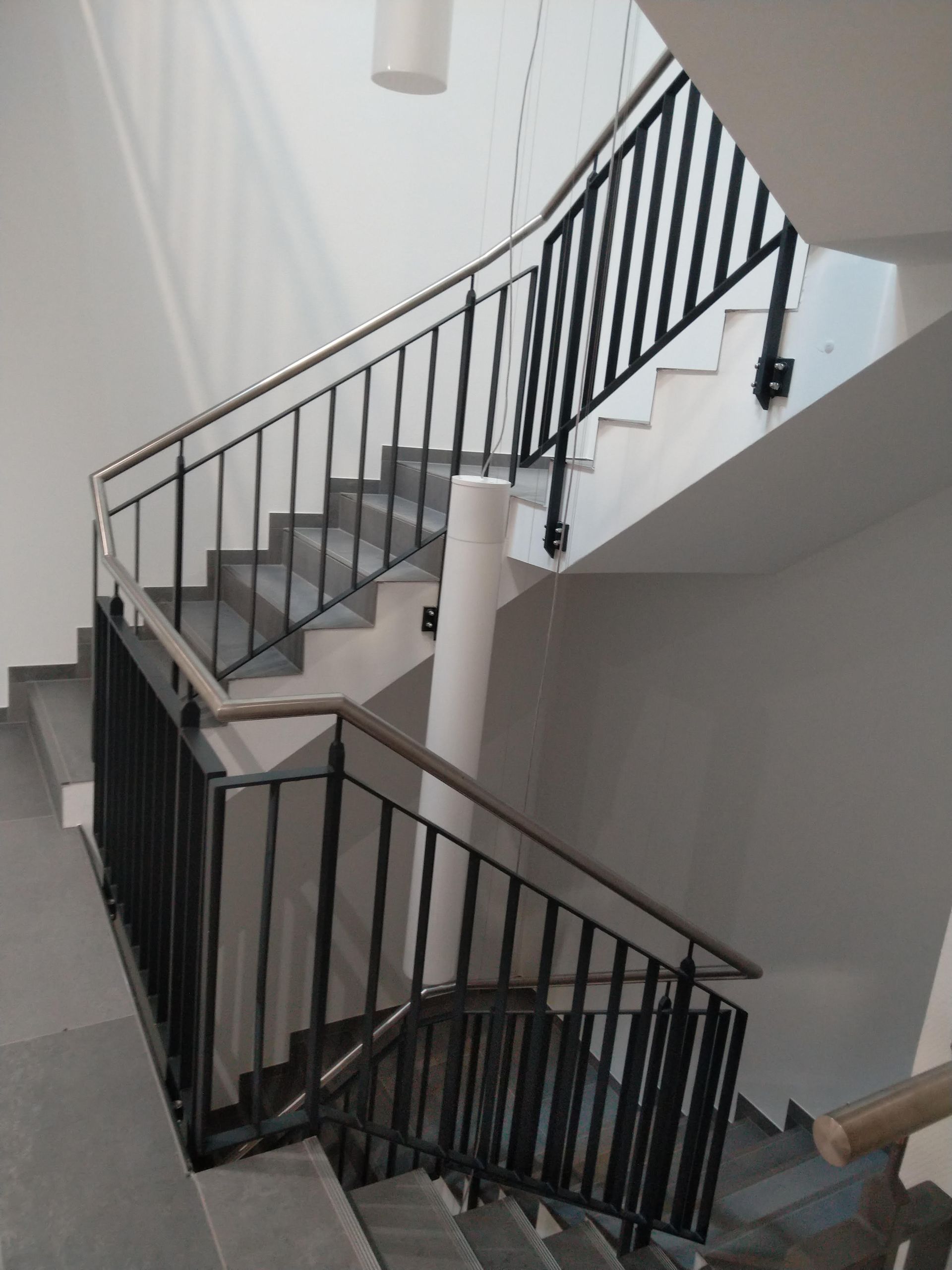 Eine Treppe mit schwarzem Geländer und Holzhandlauf