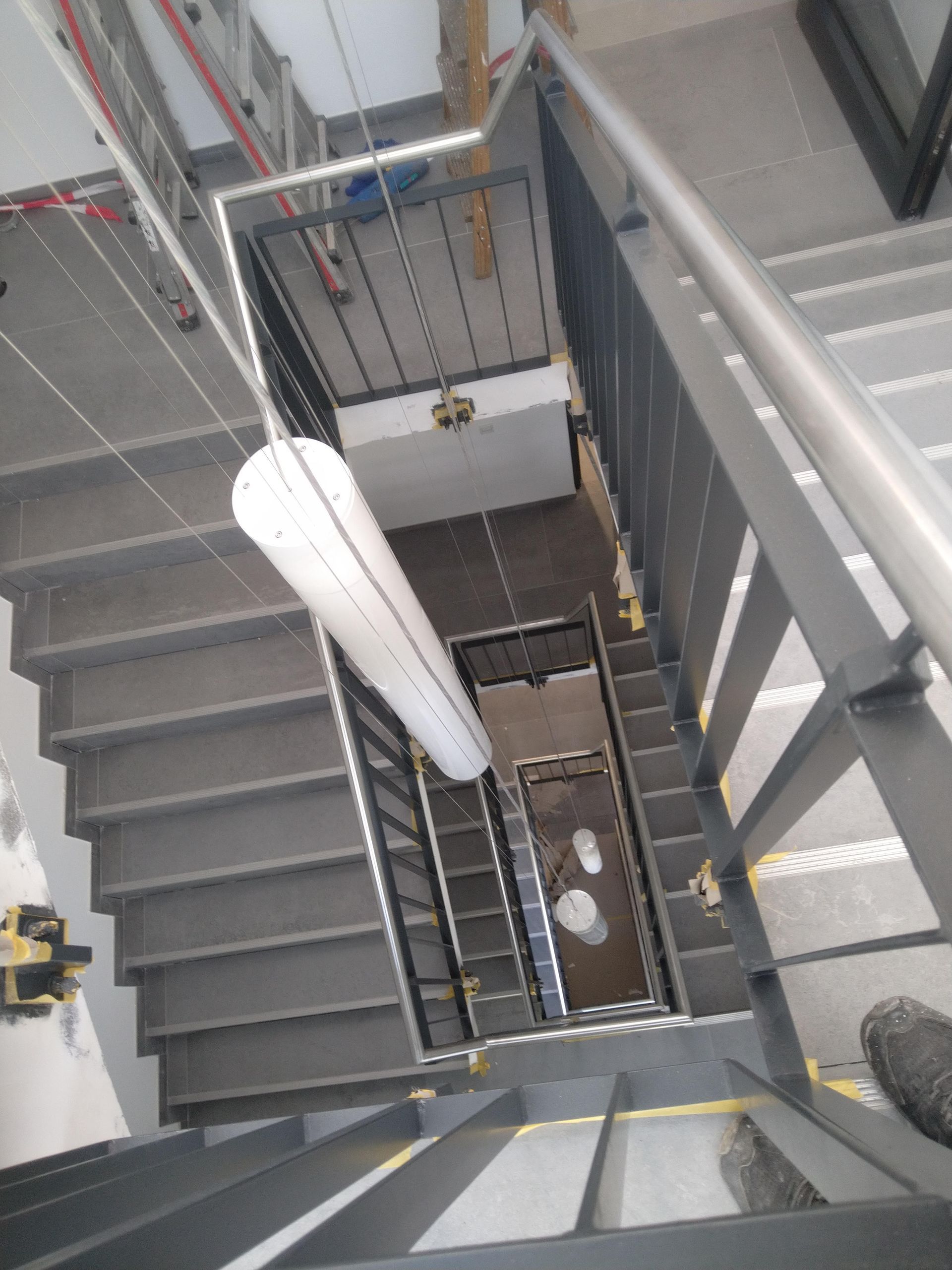 Blick eine Treppe hinunter, von der Decke hängt eine Lampe