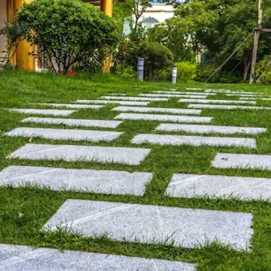 Pasos rectangulares sobre césped verde que conducen a través de un sendero de jardín.