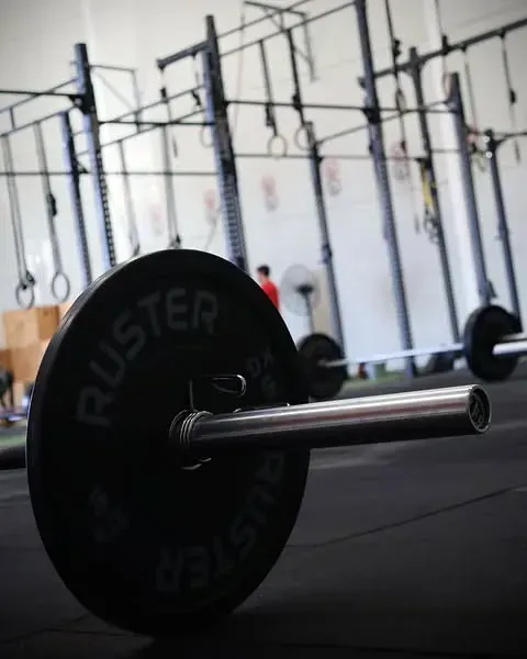 Una barra oxidada está en el suelo en un gimnasio.
