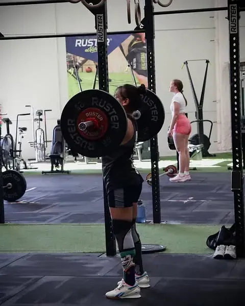 Una mujer en cuclillas con una barra que dice rustler (Custler) en ella