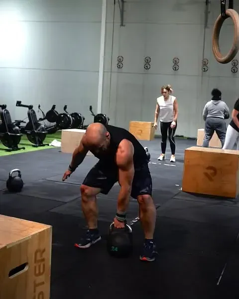 Un hombre está levantando una pesa rusa en un gimnasio.