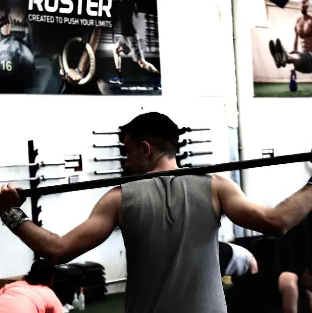 Un hombre levanta una barra frente a un cartel que dice roster