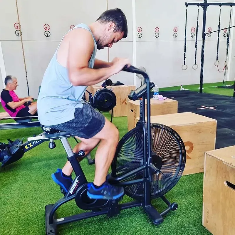 Un hombre está montando una bicicleta estática en un gimnasio.