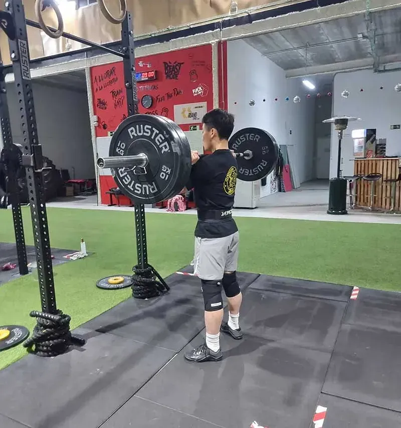 Un hombre está en cuclillas con una barra que dice rustler (Custler) en ella.