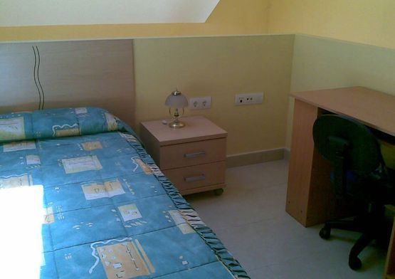 Un dormitorio con una cama, una mesita de noche y un escritorio.
