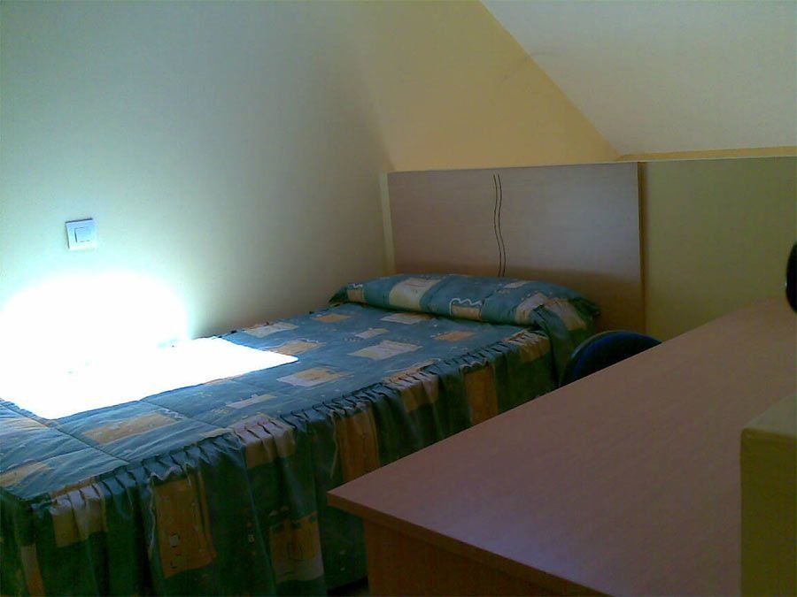 Un dormitorio con una cama, un escritorio y una silla.