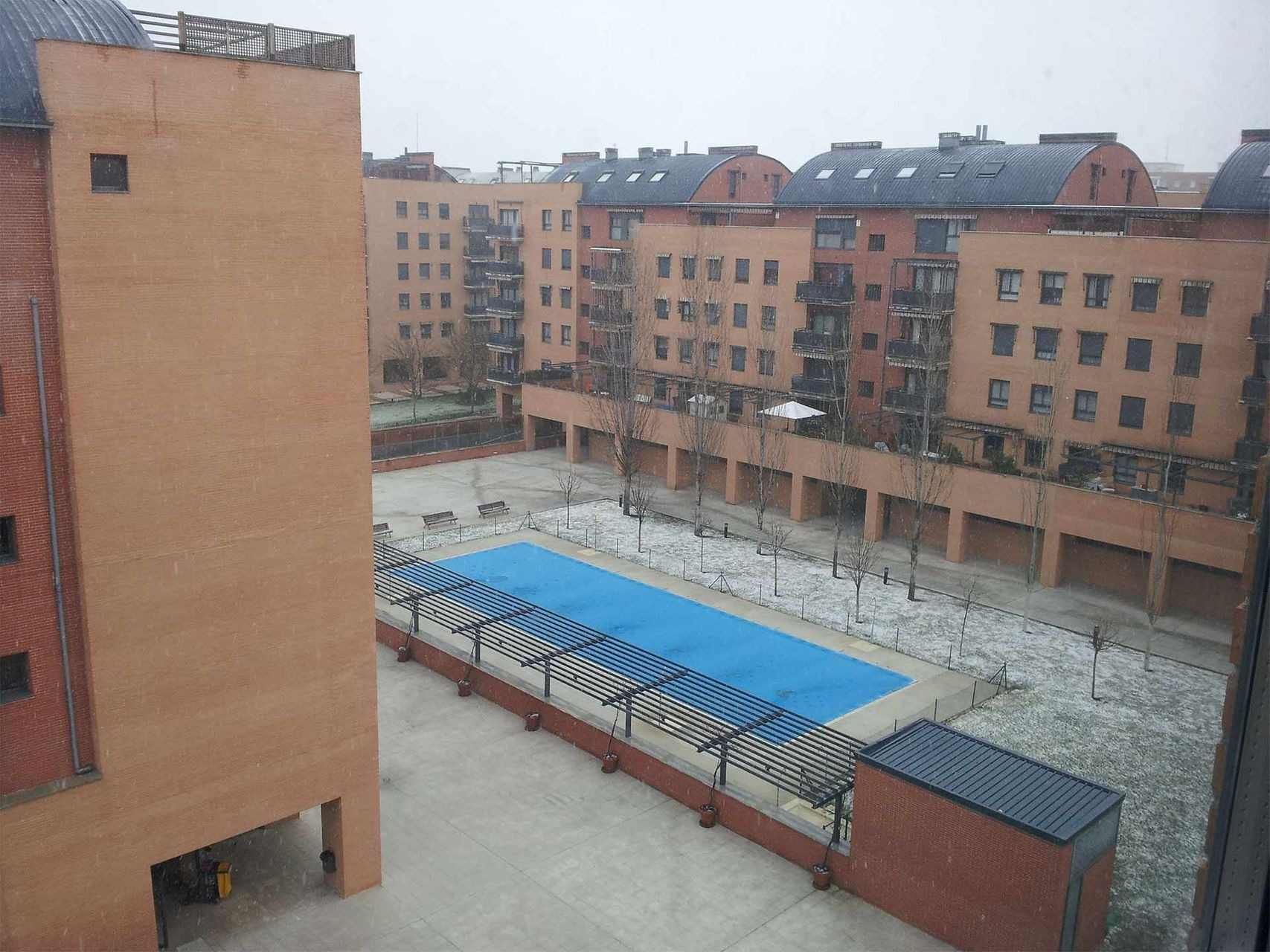 Una vista aérea de una piscina rodeada de edificios de ladrillo.