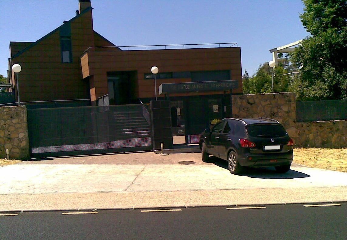 Un coche está aparcado delante de una gran casa de ladrillo.