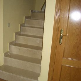 Una escalera que conduce al segundo piso de una casa al lado de una puerta.